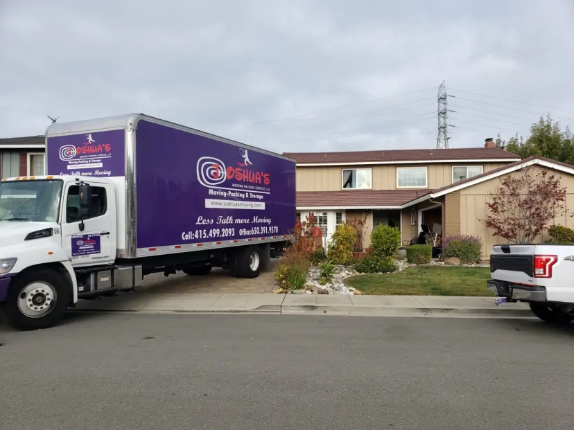 Joshua's Moving box truck parked in front of a house on a residential street