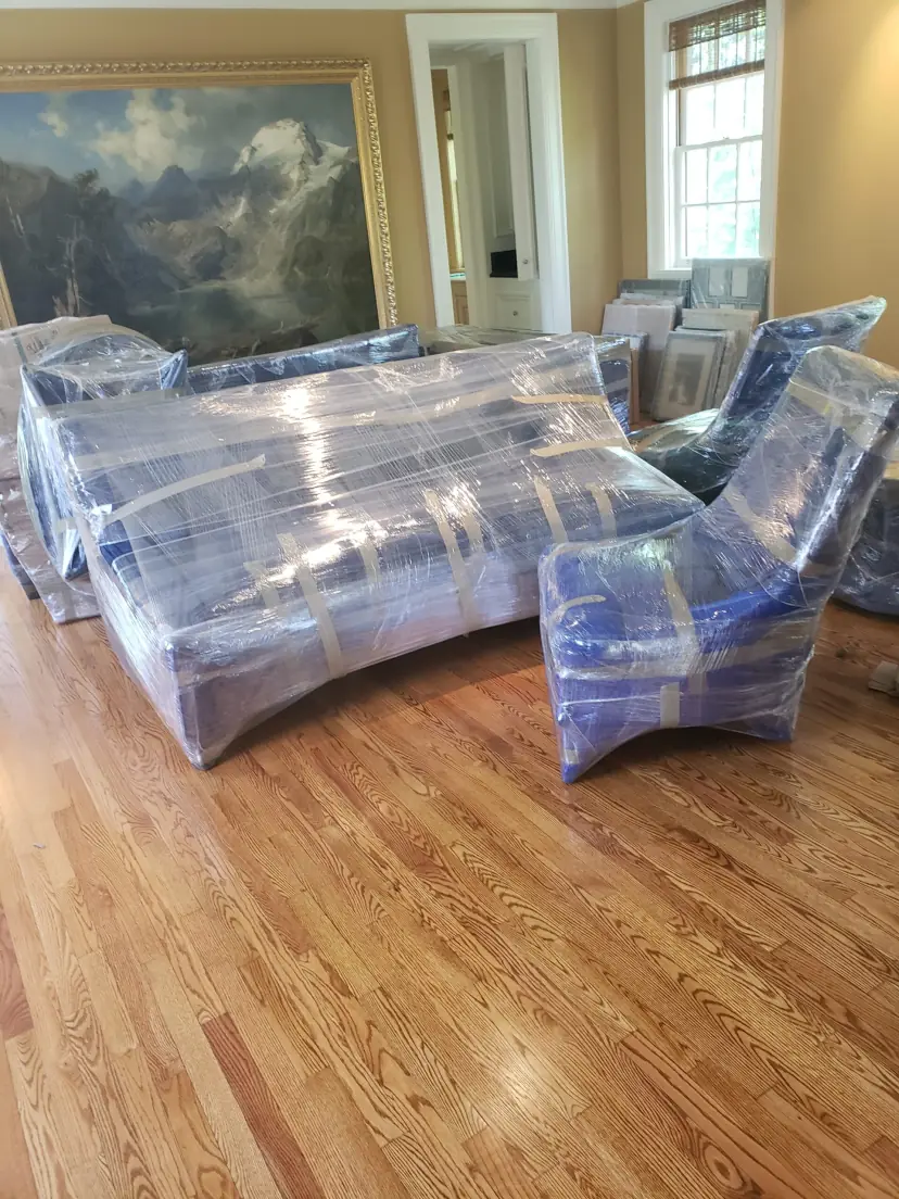Living room sofa and chairs wrapped in moving blankets and plastic, ready for an apartment move